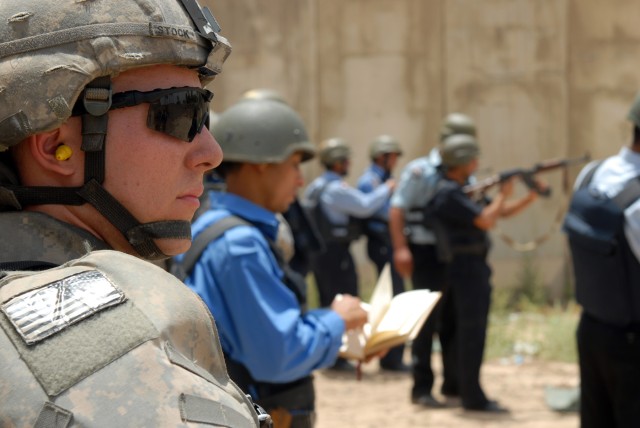 BAGHDAD - Cpl. Brian Stock, a team leader assigned to the 300th Military Police Company, 91st MP Battalion, 8th MP Brigade, looks on as Iraqi police run a firing range at Joint Security Station Shuleik, here, May 21. The weapons range was the...