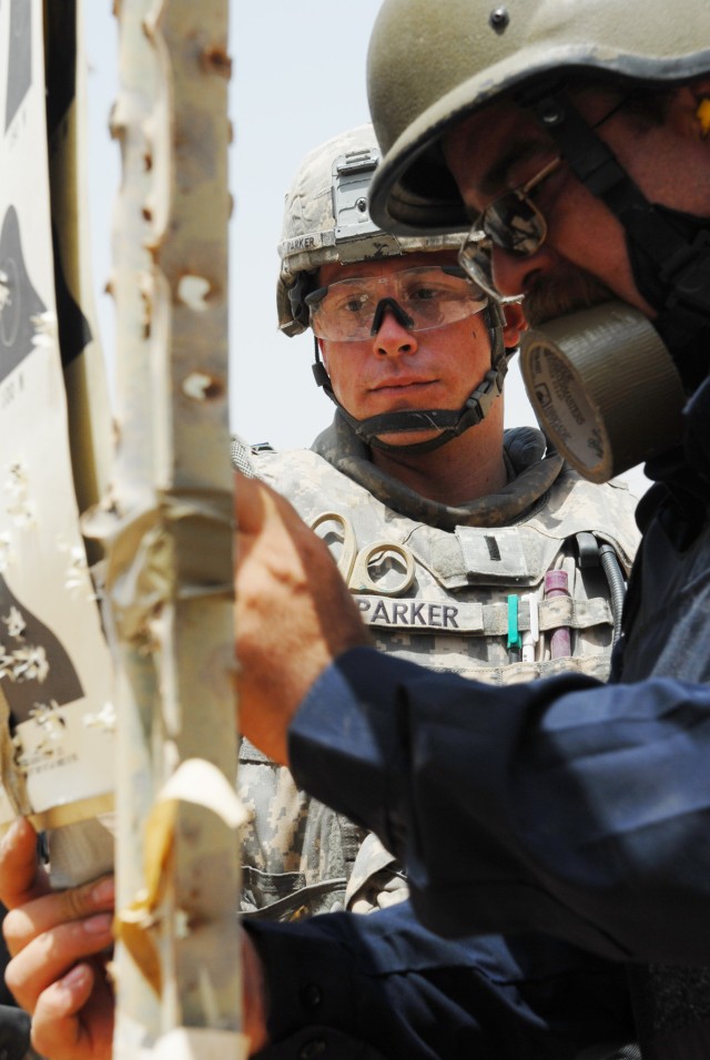 BAGHDAD - First Lt. Chris Parker, a platoon leader from Lansing, Kan., assigned to the 300th Military Police Company, 91st MP Battalion, 8th MP Brigade, helps hang up targets with Iraqi Police commissioner Ahmed Mohammed Abdullah, assigned to the...