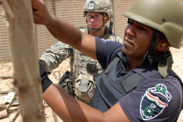BAGHDAD - First Lt. Chris Parker, a platoon leader assigned to the 300th Military Police Company, 91st MP Battalion, 8th MP Brigade, gives a hand to Iraqi policeman Barkaat Jonaa Mohassen, assigned to the al-Qahira IP Station, during the final...