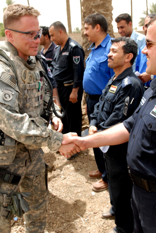 BAGHDAD - First Lt. Chris Parker, a platoon leader from Lansing, Kan., assigned to the 300th Military Police Company, 91st MP Battalion, 8th MP Brigade, congratulates an IP officer after they received an Iraqi Primary Leadership Development Course...