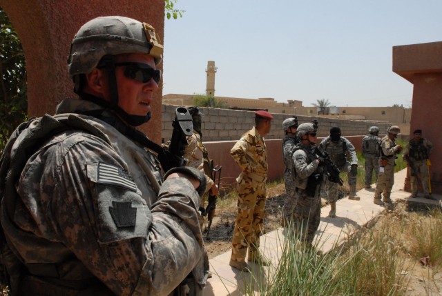 BAGHDAD - 1st Sgt. Harry Buchanan (left), of Altoona, Pa., the first sergeant of Company B, 2nd Battalion, 112th Infantry Regiment, 56th Stryker Brigade Combat Team, looks over a courtyard in Abu Ghraib, May 19, as Iraqi Army Soldiers prepare to...