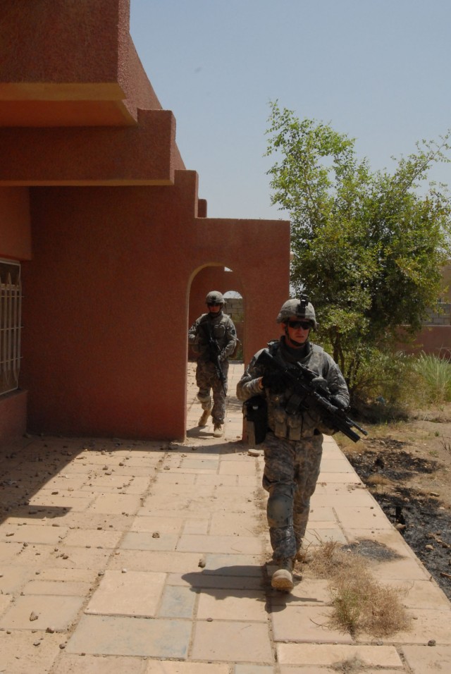 BAGHDAD - Spc. John Hill (front), of Eighty Four, Pa., and Spc. Matthew Strittmater, of Cresson, Pa., both with Company B, 2nd Battalion, 112th Infantry Regiment, 56th Stryker Brigade Combat Team, move along a building in Abu Ghraib during a...