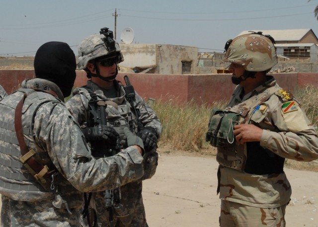 BAGHDAD - Using an interpreter (left), 1st Lt. Joshua Shearn (center), of Mount Union, Pa., with Company B, 2nd Battalion, 112th Infantry Regiment, 56th Stryker Brigade Combat Team, talks with an Iraqi Army battalion commander, May 19, during a...