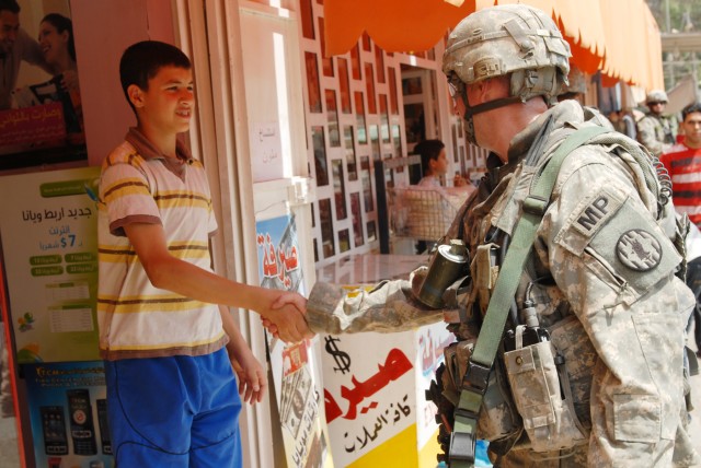 BAGHDAD - Staff Sgt. Ryan McCarthy, a military policeman and a squad leader from Wildwood, N.J., assigned to the 300th MP Company, 91st MP Battalion, 8th MP Brigade, shakes hands with an Iraqi teenager during a joint patrol at Kessler "White Rose"...