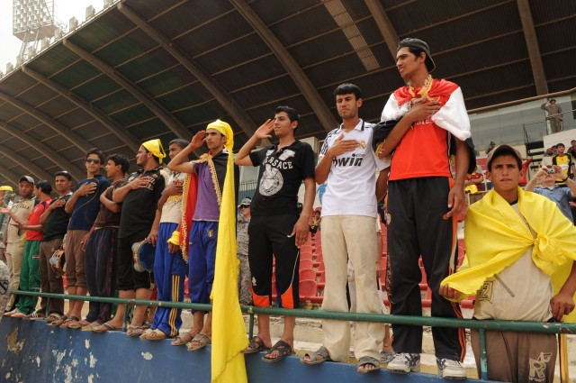 BAGHDAD - Spectators stand during the playing of the U.S. and Iraq national anthems at the opening ceremony of the FC Unity tournament at Shaab Stadium, May 22, in the Rusafa district of eastern Baghdad. Hundreds of Iraqi citizens were on hand to che...