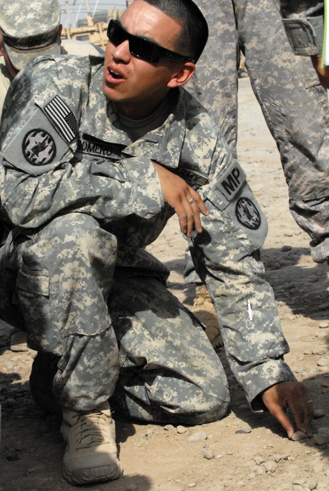 CAMP LIBERTY, Iraq - Staff Sgt. Jonathan Romero, a military policeman assigned to the 591st Military Police Company, 93rd MP Battalion, 8th MP Brigade, uses rocks to illustrate convoy operations during his mission briefing here, May 20.  "Sand...