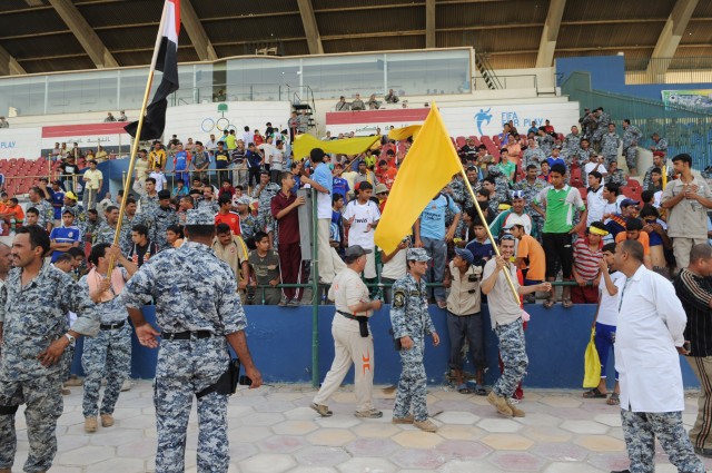 BAGHDAD - National Police officers and spectators wave flags and cheer during a game at Shaab Stadium, May 23, in the Rusafa district of eastern Baghdad. Thirty-six soccer games,32 community games and four combined U.S.-Iraqi forces games, were...