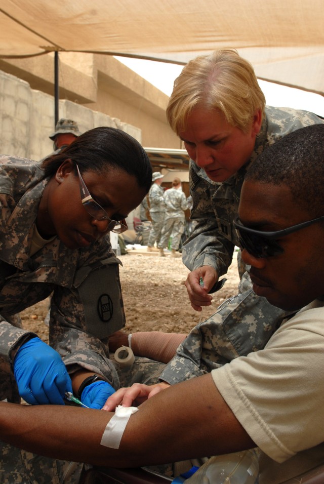BAGHDAD - Spc. Darrot Johnson (left), a medic from Tabor City, N.C., assigned to Headquarters and Headquarters Company, 252nd Combined Arms Battalion, 30th Heavy Brigade Combat Team, checks an intravenous fluid line in the arm of Spc. Dylan Zeigler, ...