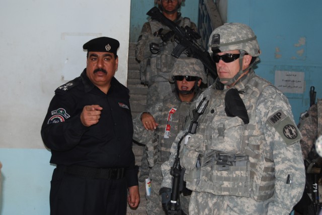 BAGHDAD - A Ma'moom Iraqi Policeman and the officer-in-charge of the crime scene briefs Coalition force partner, Lt. Col. Thomas Byrd, commander of 93rd Military Police "War Eagle" Battalion, 8th MP Brigade, Multi-National Division-Baghdad on the poi...