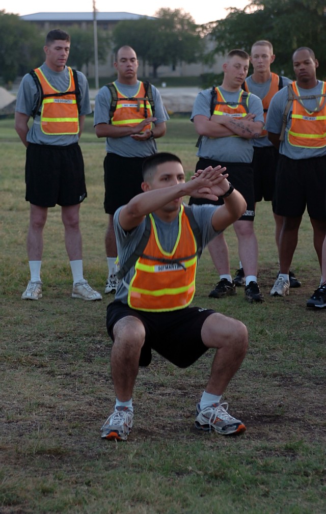 Sgt. Michael Martin, a CrossFit instructor with the Headquarters and Headquarters Company, Special Troops Battalion, 15th Sustainment Brigade, demonstrates a squat to the members of the unit June 4 during the unit's physical training session. (U.S. A...