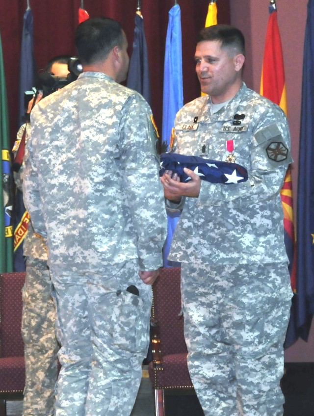 Command Sgt. Maj. Perry Clark, former command sergeant major of U.S. Army Garrison Hohenfels, accepts a flag from Lt. Col. Gary Bloomberg, garrison commander, during Clark's retirement ceremony May 14 at the Hohenfels theater. Clark said he hopes...