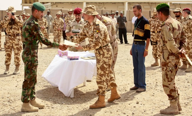 Capt. Marius Bumbac, a Romanian Army company commander and lead advisor to the Iraqi Commando Course held at Camp Dhi Qar, congratulates one of the course graduates during a ceremony held May 23. A company of Iraqi Commandos graduated from the Romani...