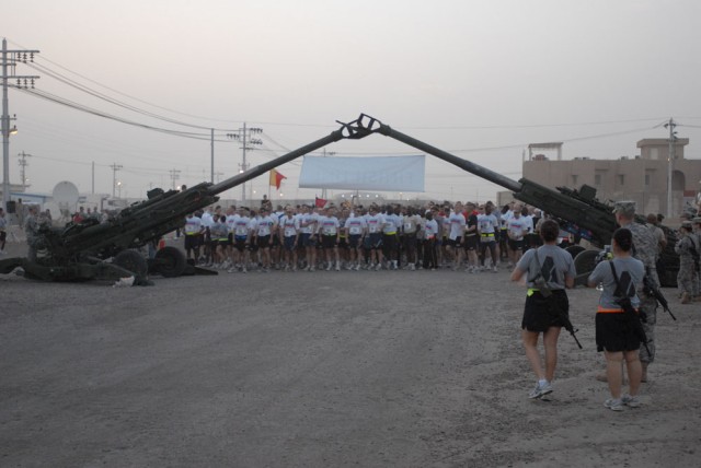 CAMP TAJI, Iraq - Under the arch of artillery cannons, Soldiers ready themselves along the starting line in the early morning hours to begin the 108th Field Artillery Memorial Day Marathon.  The Los Angeles Marathon organizers sponsored the race prov...