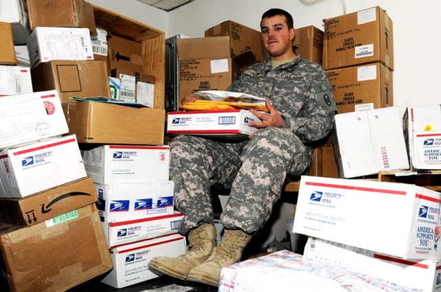 BAGHDAD - Surrounded by incoming mail, Pfc. Michael Lyjak, of Monroe, N.C., sorts packages in his office at Forward Operating Base Falcon in Iraq, May 15. Lyjak, the mail clerk for Headquarters and Headquarters Company, 30th Heavy Brigade Combat Team...