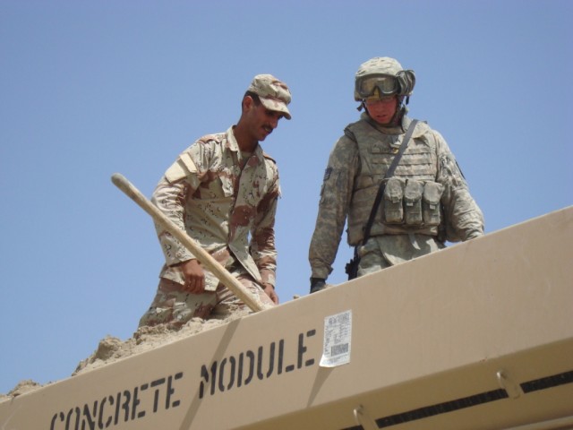 BAGHDAD - Sgt. Gabriel Lopez (right), a concrete and asphalt team leader with 46th Engineer Combat Battalion (Heavy), 225th Engineer Brigade, from Sacramento, Calif., shows an Iraqi engineer how to keep sand and gravel mixtures flowing correctly thro...