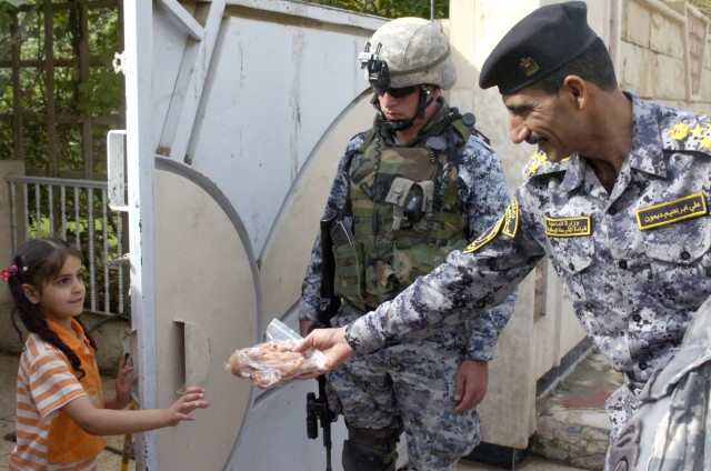 BAGHDAD - Iraqi Brig. Gen. Ali Ibraheem Dabown (right), commander of the 8th National Police Brigade, 2nd NP Division, gives an Iraqi girl a stuffed animal during Operation Asfah Ramlyah, a combined clearance operation, May 28, in the neighborhood...