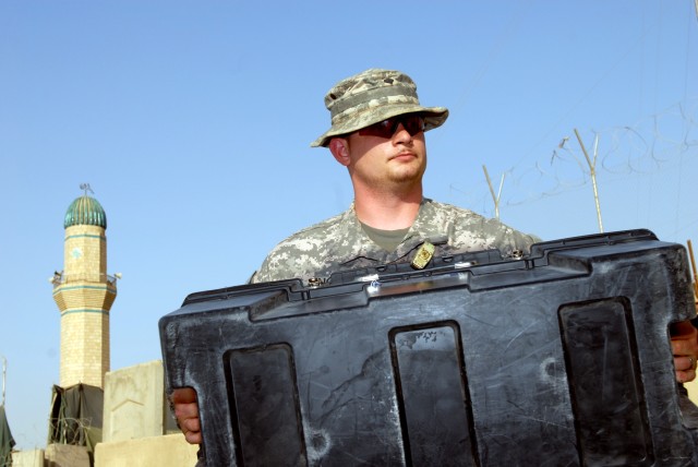 BAGHDAD - As a minaret sounds the call to prayer in the background, Spc. Tyler Ring, an armorer, assigned to Headquarters and Headquarters Company, 2nd Squadron, 5th Cavalry Regiment, 1st Brigade Combat Team, 1st Cavalry Division, moves a box, May...