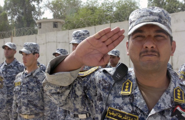 BAGHDAD - A National Police officer assigned to the 3rd Regiment, 1st NP Battalion, 1st NP Brigade, renders a salute during the playing of the Iraqi national anthem as he and his fellow NPs stand in formation during the transfer ceremony of Joint Sec...