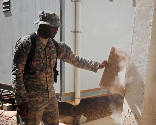 BAGHDAD - Spc. Jason Givens, a supply sergeant's assistant with Headquarters and Headquarters Company, 120th Combined Arms Battalion, 30th Heavy Brigade Combat Team, Multi-National Division-Baghdad, tries to remove sand and debris from the supply off...