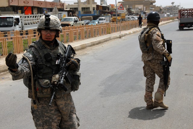 BAGHDAD - Staff Sgt. Joseph Lopez, an infantryman section leader from Harlingen, Texas, stops traffic as an Iraqi Army Soldier secures the other direction while on patrol in Sadr City, here, May 27. Lopez and his Soldiers are constantly patrolling...