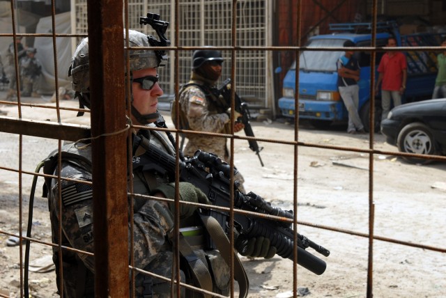 BAGHDAD - Cpl. Shane Smith, an infantryman team leader from Worcester, Mass., assigned to Company B, 2nd Battalion, 5th Cavalry Regiment, 1st Brigade Combat Team, 1st Cavalry Division, secures the area as an Iraqi Army Soldier also keeps watch in...