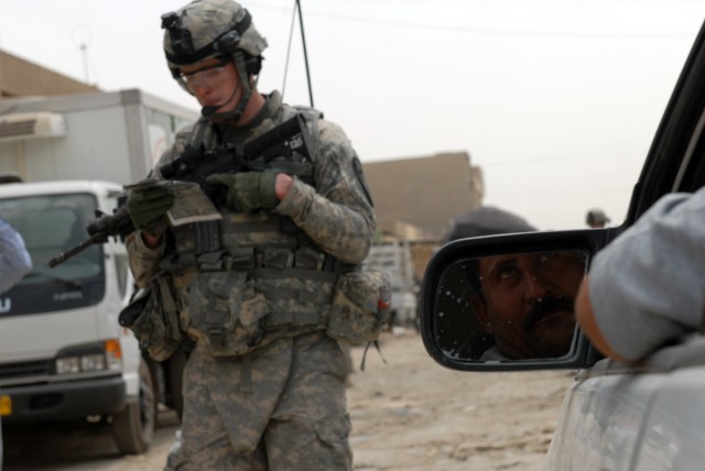 BAGHDAD - A taxi cab driver looks on as Pfc. Daniel Owen, an infantryman and radio telephone operator from Eaton Rapids, Mich., assigned to Co Company B, 2nd Battalion, 5th Cavalry Regiment, 1st Brigade Combat Team, 1st Cavalry Division, takes a...