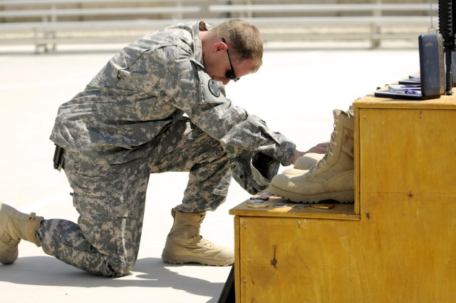 BAGHDAD-Maj. Toby Clifton, of Headquarters and Headquarters Company, 30th Heavy Brigade Combat Team, kneels in front of a memorial to the three brigade Soldiers killed by a bomb, May 21.  The May 29 memorial service, at Forward Operating Base Falcon,...