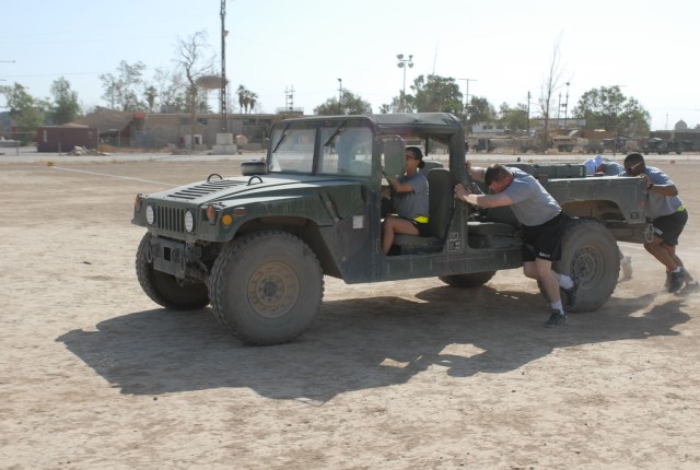 Soldiers from Headquarters and Headquarters Company, 2nd Brigade Combat Team, 1st Cavalry Division, push a humvee as part of the Commander's Cup, during the last day of events May 24 at Forward Operating Base Warrior's Mountain Warrior Gym. The Comma...