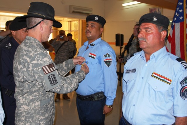 Lt. Col. Terry Cook, the commander of 3rd Battalion, 82nd Field Artillery Regiment, 2nd Brigade Combat Team, 1st Cavalry Division, pins Commissioner Hameed Hermis, an Iraqi police officer, with an Army Achievement Medal during a ceremony at the...