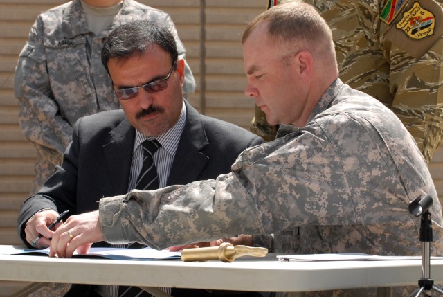 BAGHDAD -- Lt. Col. John Vermeesch (right), a Roscommon, Mich., native and commander of 1st Battalion, 18th Infantry Regiment, 2nd Brigade Combat Team, 1st Infantry Division, prepares to sign transfer contracts with Samir Hadad, the secretary...