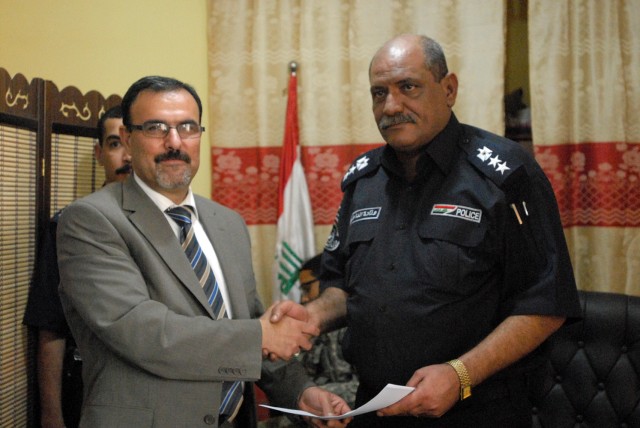 BAGHDAD- Iraqi Col. Mohmad Laeftah Fleh (right), the director of Shaab Police Station, shakes hands with the Prime Minister of Iraq's representative, after signing for the responsibility of Joint Security Station Shaab, May 28. JSS Shaab is one...