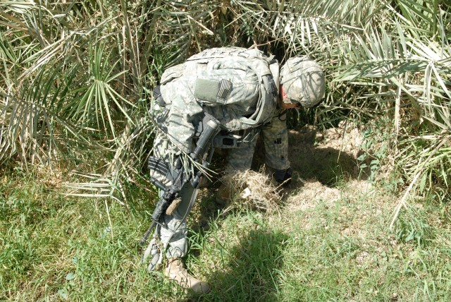 BAGHDAD - First Lt. Joe Zoretic of Nashville, Tenn., a platoon leader assigned to Battery B, 1st Battalion, 82nd Field Artillery Regiment, 3rd Brigade Combat Team, 82nd Airborne Division, searches a spot in a field in Jisr Diyala where a weapons...