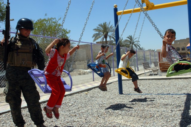 BAGHDAD - Iraqi Army Pvt. Abass Fadal Juwad, an infantryman assigned to 3rd Battalion, 44th Brigade, 11th Iraqi Army Division, takes a moment to play with some Iraqi children while on patrol with Soldiers of 2nd Battalion, 5th Cavalry Regiment,...