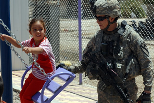BAGHDAD - Spc. Edward Suarez, a tanker from Phelan, Calif., assigned to Company B, 2nd Battalion, 5th Cavalry Regiment, 1st Brigade Combat Team, 1st Cavalry Division, gives a push to an Iraqi girl at a recently finished playground funded by CF in...