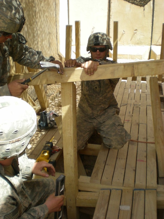 BAGHDAD - Carroll, Iowa native, Spc. Cory Riesenberg, a carpentery/masonry specialist, 46th Engineer Combat Battalion (Heavy), 225th Engineer Brigade, holds a railing in place outside the tactical operating center at Patrol Base Yusifiyah, while...