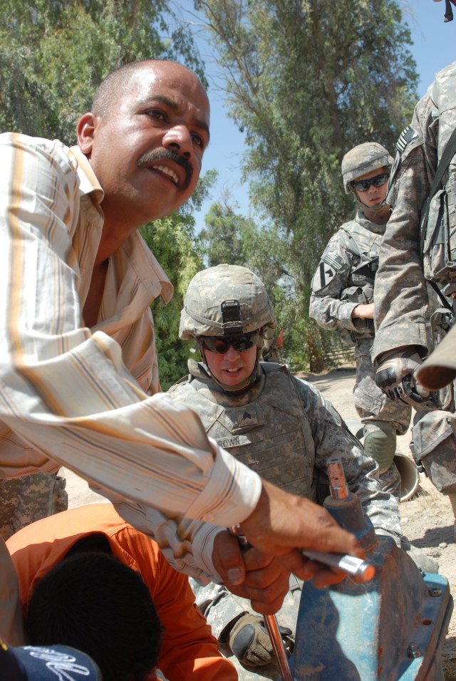 BAGHDAD - Sgt. James Brown of Binghampton, N.Y., a track vehicle mechanic assigned to Company G, 1st Battalion, 82nd Field Artillery Regiment, 3rd Brigade Combat Team, 82nd Airborne Division, oversees an Iraqi volunteer repair a broken valve at...