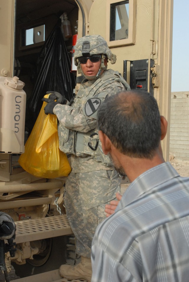 Pfc Anthony Mariscal, a Houston native and a tanker mechanic with Company C, Battalion, 8th Cavalry Regiment, 2nd Brigade Combat Team, 1st Cavalry Division, distributes food from the back of his vehicle in the village of Qushquaya, Iraq, May 29....