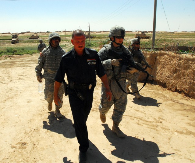 Lt. Abbas (left) of the Daquq, Iraq Police and 1st Lt. Christopher Minter (right), from New Kent, Va., and a platoon leader in C Troop, 4th Squadron, 9th Cavalry Regiment, 2nd Brigade Combat Team, 1st Cavalry Division, travel together in a...