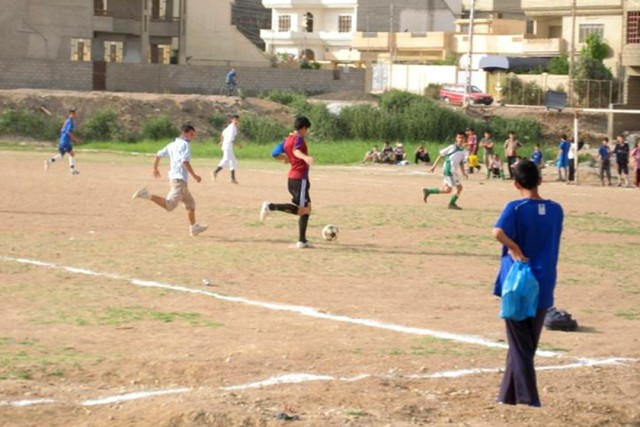 Iraqi children kick up a game of soccer on their new soccer field, which was completed and opened for use in the 7 Nissan neighborhood of Mosul May 30. Coalition forces coordinated with neighborhood locals to help fund and build the soccer field,...