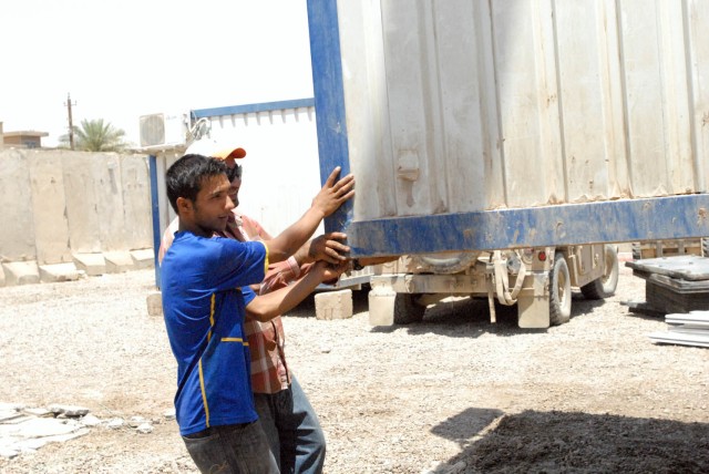 BAGHDAD-Iraqi contractors assist in moving a containerized housing unit, June 2, in order to help Company E , 1st Battalion, 5th Cavalry Regiment, attached to the 1st Brigade Combat Team, 1st Cavalry Division, move out of Joint Security Station Basat...