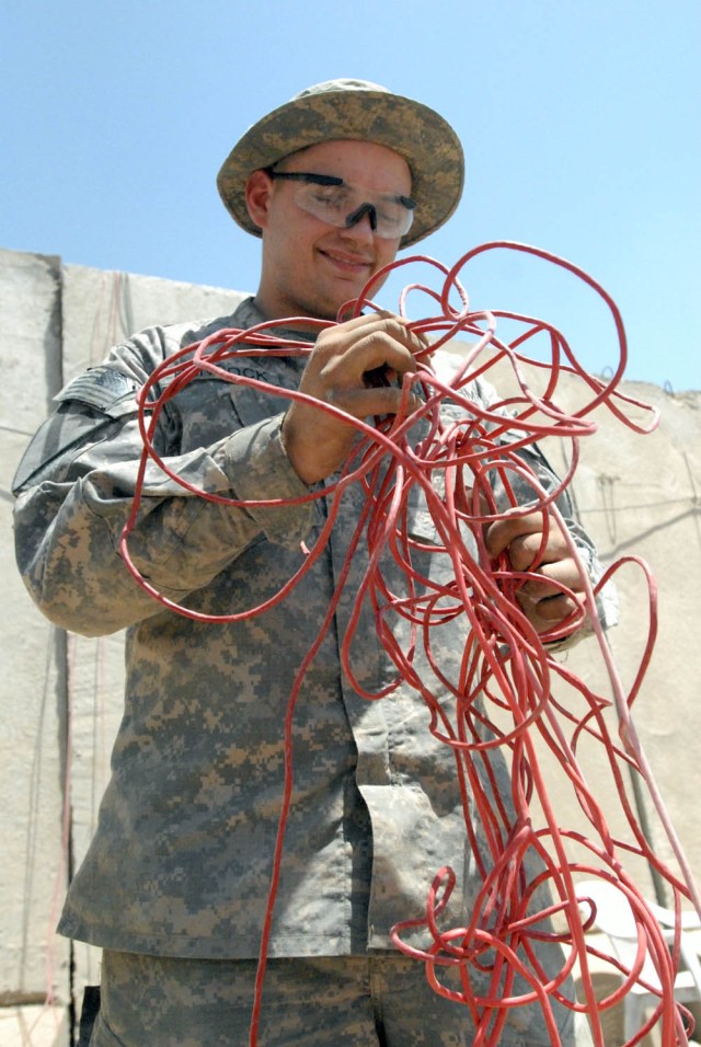 BAGHDAD - Dallas, Texas native, Pfc. Blaine Hancock, a communication specialist with Company E, 1st Battalion, 5th Cavalry Regiment, attached to the 1st Brigade Combat Team, 1st Cavalry Division, rolls up the computer wire from the old containerized ...
