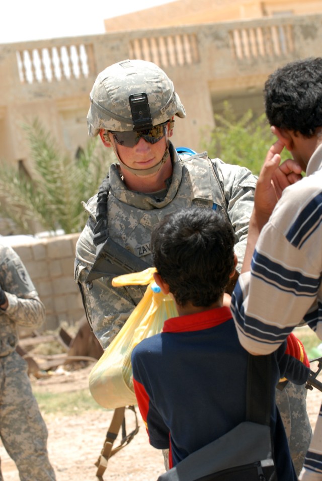 BAGHDAD - Pfc. Ross Zavoyna, an infantryman assigned to Headquarters and Headquarters Company, 2nd Battalion, 8th Cavalry Regiment, 1st Cavalry Division, gives a child a bag of food for his family after the ground breaking ceremony at the Zoba...