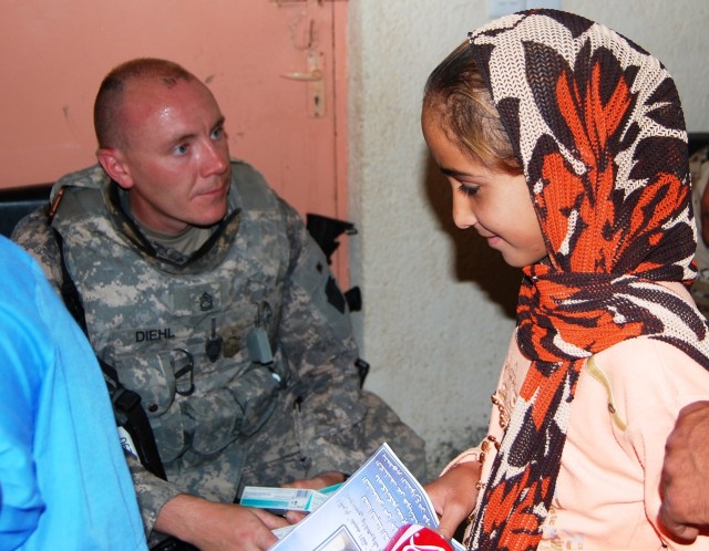 TAJI, Iraq -Staff Sgt. Christopher Diehl, of York, Pa., 328th Brigade Support Battalion, 56th Stryker Brigade Combat Team, Multi-National Division-Baghdad, hands supplies to a young girl at the school at the al-Boreyap, June 4.  Diehl and his unit...