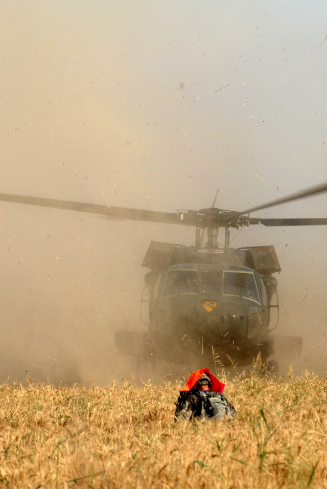 BAGHDAD - A Soldier of B Troop, 2nd Battalion, 8th Cavalry Regiment, 2nd Brigade Combat Team, 1st Infantry Division, stands in a wheat field amid the rotor wash and flying debris to mark the spot for the UH-60 Blackhawk helicopter to land, June 3.  T...