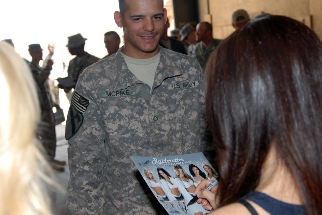 BAGHDAD - Pfc. Chance McPike, of Troy, Mo., a generator mechanic assigned to Headquarters Support Company, Division Special Troops Battalion, 1st Cavalry Division, Multi-National Division-Baghdad, waits for autographs from the Oakland Raiderettes,...