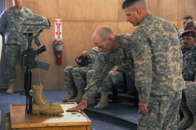 BAGHDAD - Capt. Steve Smith (left), places an 82nd Airborne Division unit patch on the memorial for Sgt. Justin Duffy, June 7, at Joint Security Station Loyalty, located in the 9 Nissan district of eastern Baghdad. Capt. Smith, along with Sgt. 1st...