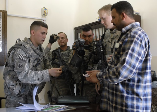BAGHDAD - Staff Sgt. Samuel Lorenz (left), a native of Mercer, Pa., 2nd Battalion, 8th Cavalry Regiment, attached to the 2nd Heavy Brigade Combat Team, 1st Infantry Division, Multi-National Division-Baghdad, pays an Iraqi businessman money from a sma...