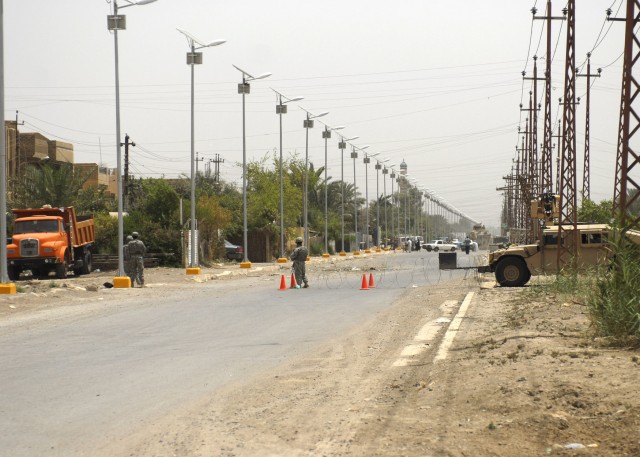 BAGHDAD - Soldiers serving with the 5th Squadron, 4th Cavalry Division, 2nd Heavy Brigade Combat Team, 1st Infantry Division, Multi-National Division-Baghdad, oversee solar lights being installed on a street in the Ghazaliyah neighborhood of northwes...