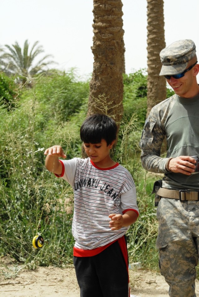 BAGHDAD - Spc. Joshua Brister (right), of Dry Prong, La., 225th Engineer Brigade, laughs as Ali, a young Iraqi boy, shows off yo-yo skills, June 6. When Ali began playing with the yo-yo, it quickly became obvious it was not his first spin with the...