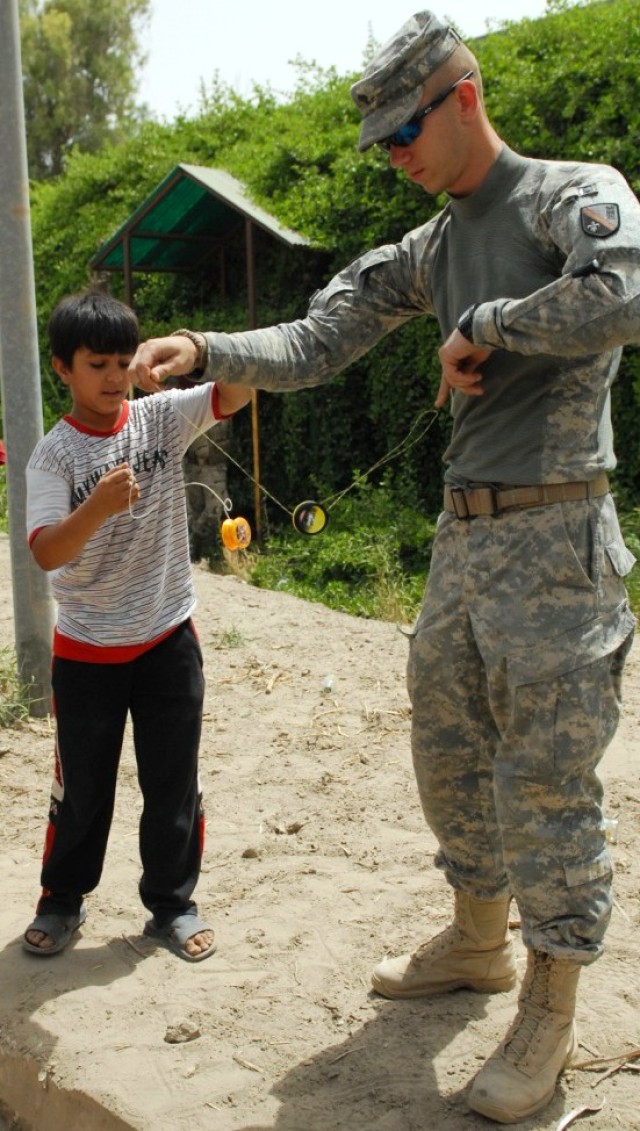 BAGHDAD - Ali, a young Iraqi, and Spc. Joshua Brister, of Dry Prong, La., 225th Engineer Brigade, trade yo-yo tricks, June 6. The personnel security detachment Soldier was waiting in front of Salam Palace, here, playing with the yo-yo when the...